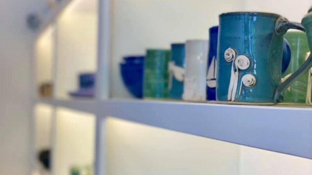 close up shot of pottery mugs and bowls on a white shelf