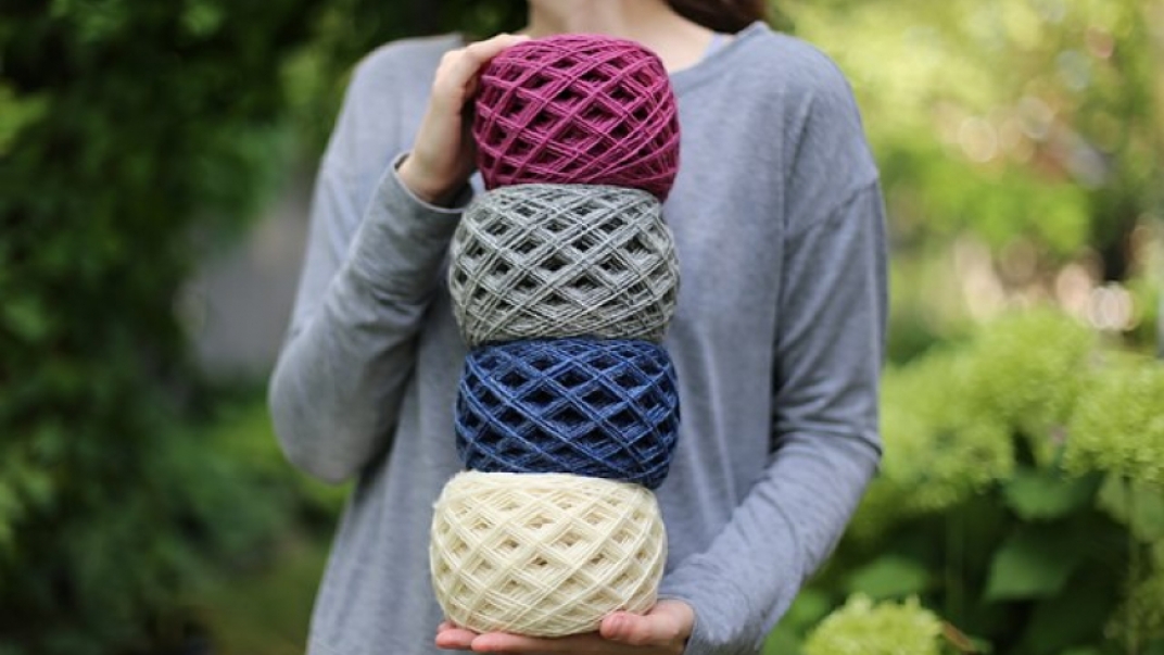 Woman holding four bundles of woolen yarn