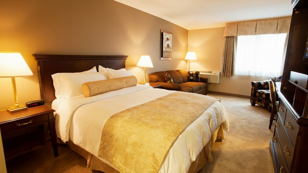 Interior shot of a hotel room with a luxurious bed with white and gold blankets.