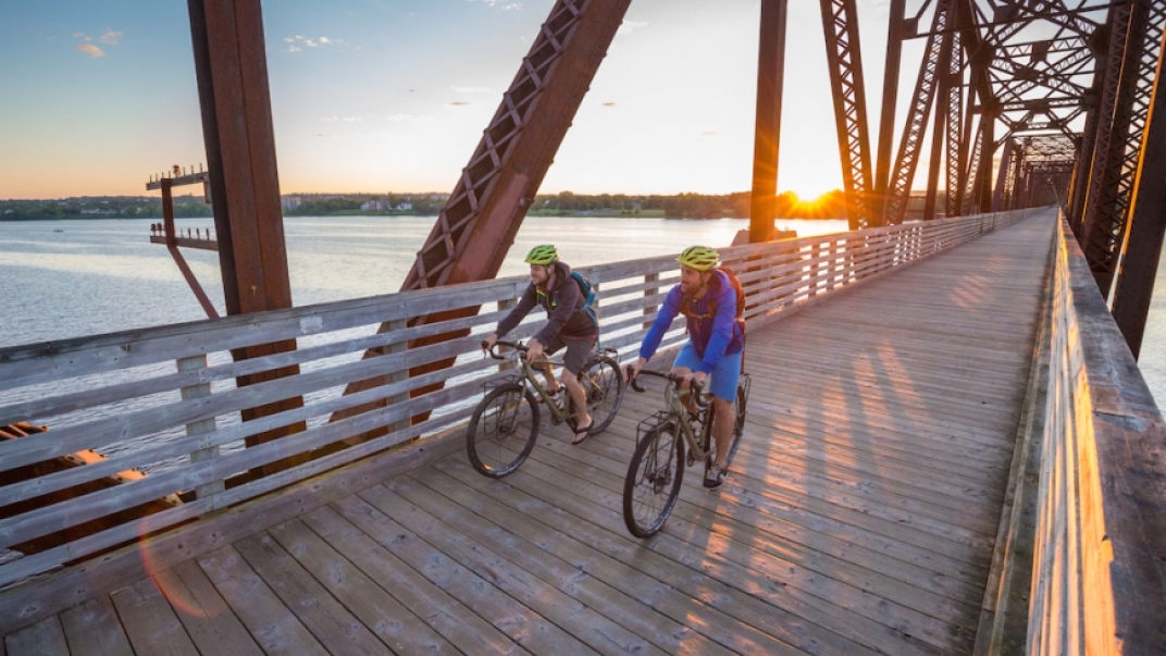 Two people riding bikes over bridge