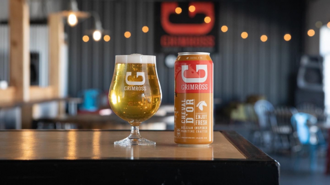 glass and can of grimross beer on a counter with a blurred background