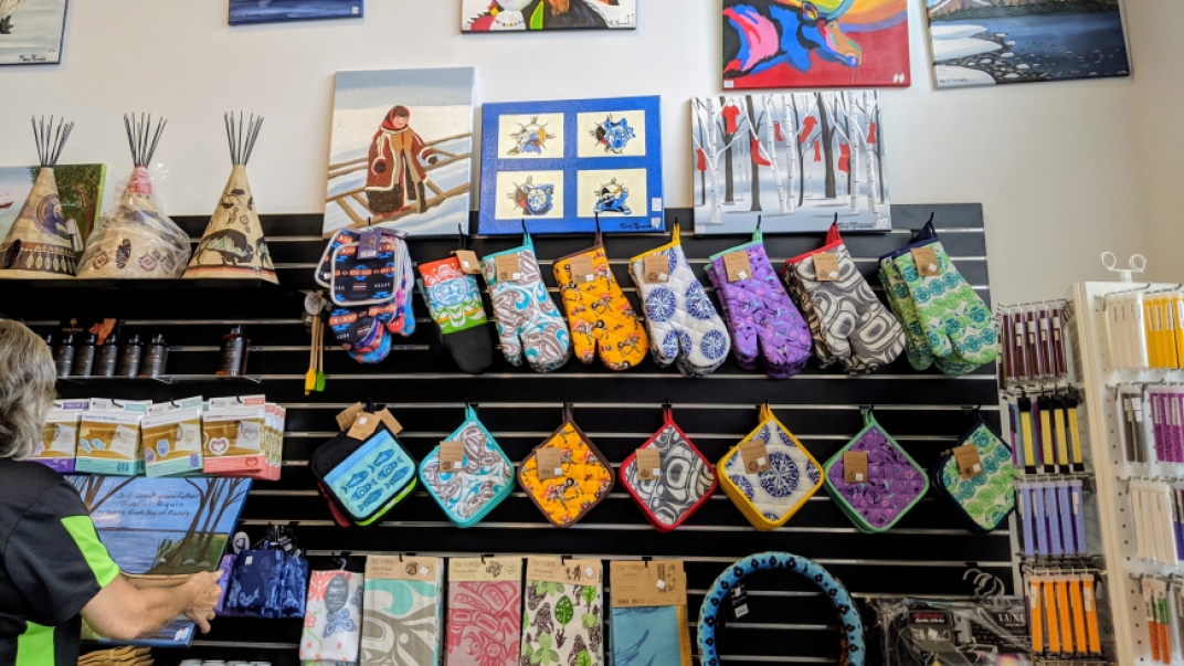 wall of wares including art, colourful patterned oven mitts and tea towels