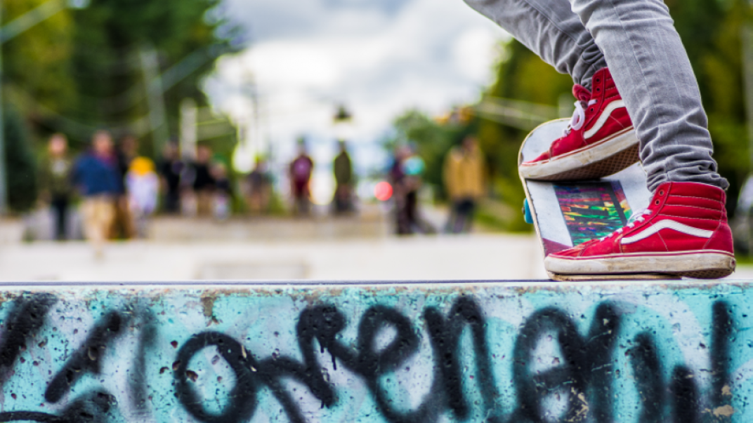 close up shot of a person wearing bright red vans on a skateboard about to drop into the skate bowl