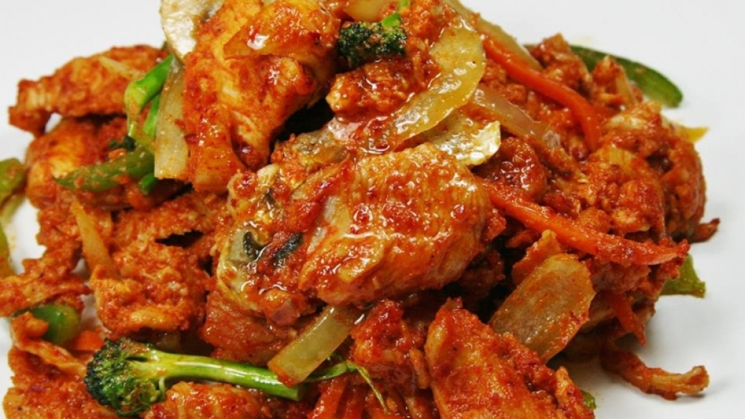 a tomato based curry dish with broccoli and onions