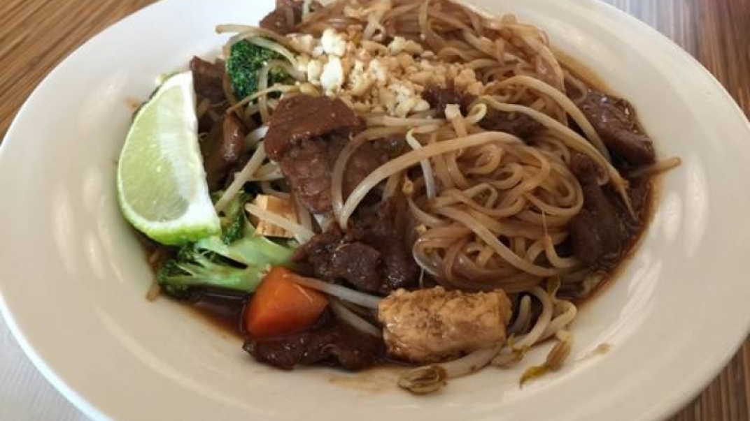 White bowl with noodles, beef and vegetables in it