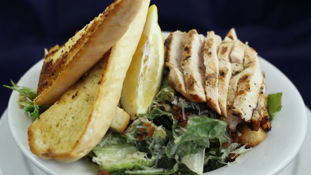 plate of chicken caesar salade and garlic bread