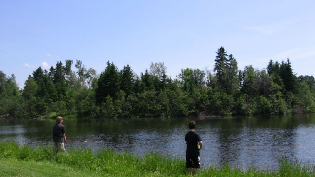 two men fishing at the edge of a river in a park