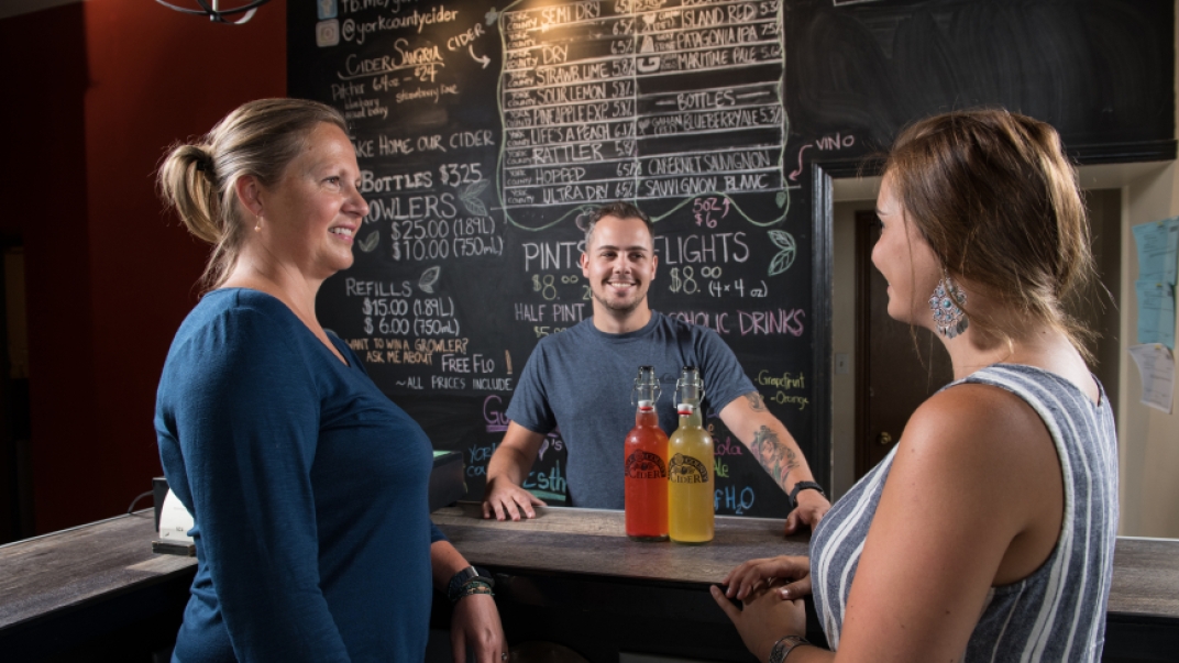 a man and two women standing in front of a chalkboard menu