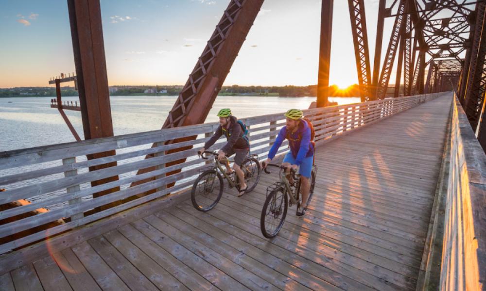 Two people riding bikes over bridge
