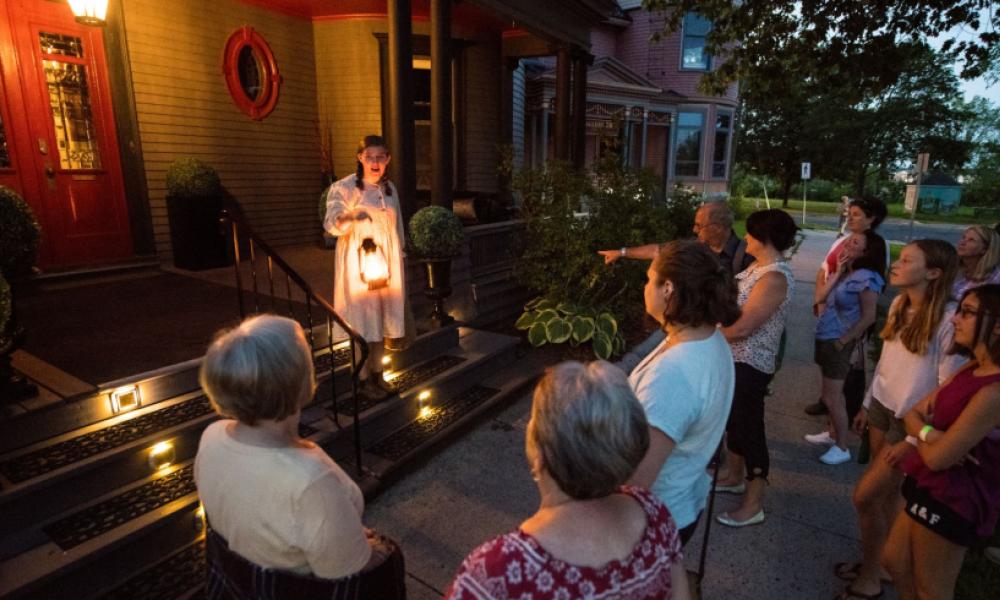 Tour guide holding a lantern narrating haunted stories to a captive audience