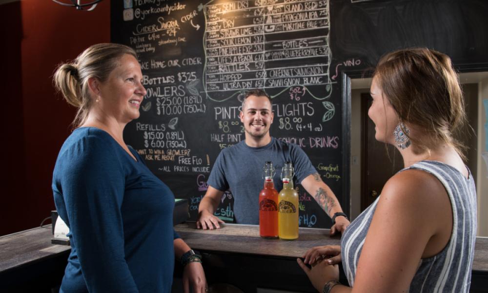 a man and two women standing in front of a chalkboard menu